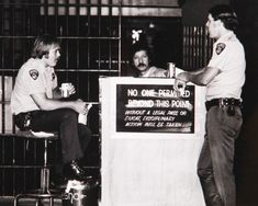 two men sitting at a counter talking to each other in front of a jail cell