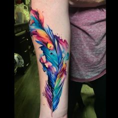 a colorful feather tattoo on the arm