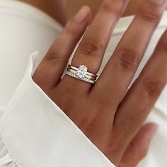 a woman's hand with a diamond ring on her left hand, wearing a white dress shirt