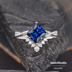 a blue diamond ring sitting on top of a piece of rock with diamonds around it