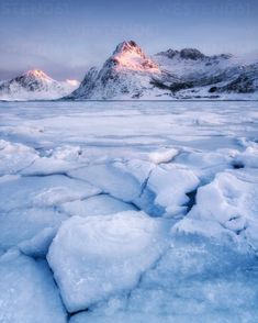 the mountains are covered in snow and ice floes at sunset, with small chunks of ice on the ground