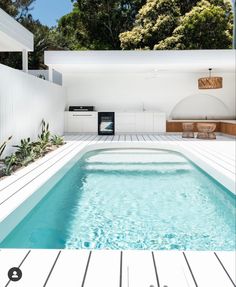 an empty swimming pool in the middle of a backyard with white walls and wood flooring