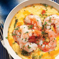 a white bowl filled with shrimp and grits on top of a blue place mat