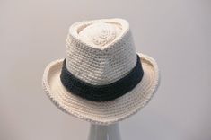 a white crocheted hat with a black ribbon around the brimmed band