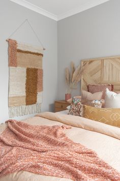 a bed with pillows and blankets on top of it next to a wooden headboard