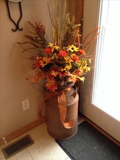 a vase filled with lots of flowers sitting on top of a door mat next to a clock