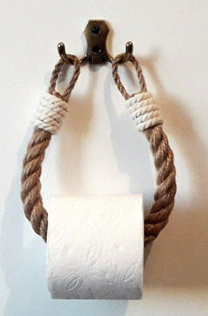 a white toilet paper roll sitting on top of a rope wrapped wall mounted holder with two metal handles