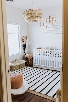 a baby's room with a white crib, black and white striped rug, gold chandelier