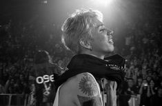 a black and white photo of a man with tattoos on his arm in front of an audience