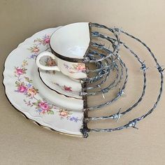 a stack of tea cups and saucers with barbed wire