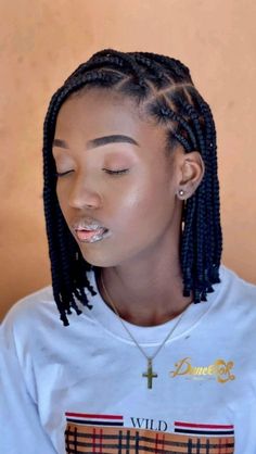 a woman with long box braids wearing a white t - shirt and silver necklace