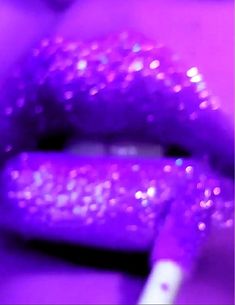 a close up view of purple lipstick with glitter on it's lips and the tip of a pen sticking out