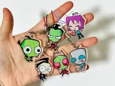 a hand holding several cartoon key chains in it's palm, with the characters on them