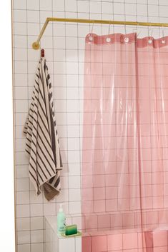 a bathroom with pink and white tiles, a shower curtain and a towel hanging on the wall