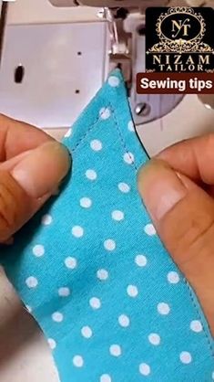 someone is sewing on a blue polka dot fabric with a sewing machine in the background