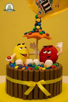 a cake decorated to look like an umbrella and two fruit characters on top of it