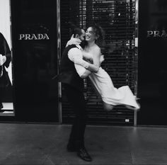 black and white photograph of a couple kissing in front of a prada storefront