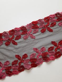 a piece of cloth with red flowers on it and grey fabric around the edges that has been sewn together