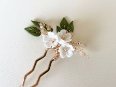 "CL1002 WHITE FLOWER/GREEN LEAF PIN  This beautiful floral gold bridal hair pin has been made with white porcelain flowers, green polymer clay leaves and champagne coloured crystal beads. A beautiful accessory for your wedding or other special occasion!  PRODUCT DETAILS Dimensions are approximately 2.75\" (7 cm) (W) x 4\" (10 cm) (H) PRODUCTION Each hair piece is handmade to order and therefore there may be slight variations from the listing photo." Outdoor Wedding Hair, White Flower Wedding, Clay Leaves, Flower Wedding Hair, Wedding Hair Pin, Beads Style, Gold Hair Pin, Bridal Hair Piece, Flower Hair Comb