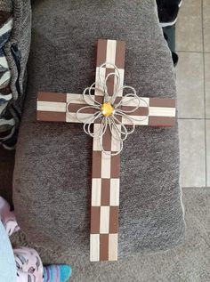 a wooden cross sitting on top of a gray couch next to a child's foot