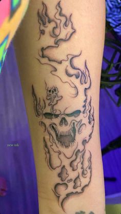 a tattoo on the leg of a person with a skull and flames in it's head