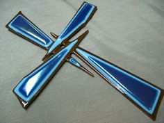 a blue cross shaped brooch with scissors on it