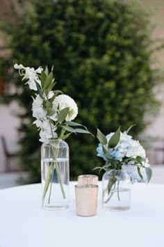 two vases filled with flowers sitting on top of a white table next to each other