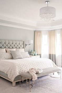 a bedroom with gray walls and white bedding in the center, along with a chandelier hanging from the ceiling