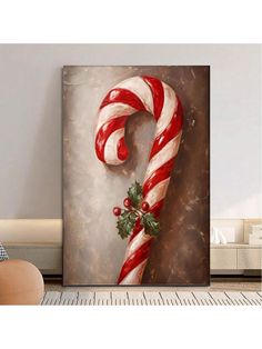 a christmas candy cane with holly on it in front of a wall mounted art piece