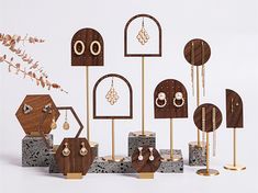 a group of wooden jewelry stands on top of cement blocks with gold earring holders