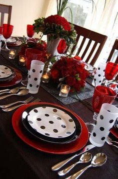 the table is set with black and white polka dot plates, silverware, and red candlesticks