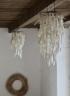 two chandeliers hanging from the ceiling in a room with white walls and wood beams