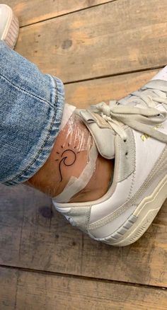 a person's foot with a small tattoo on their left leg and the bottom part of her shoe covered in plastic