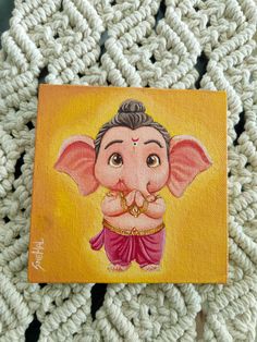 an elephant painted on top of a piece of wood next to a crocheted blanket