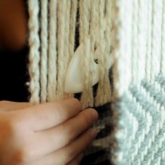 a person is weaving on a large piece of yarn with their hands and the end of an object in front of them