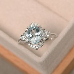 an engagement ring with a blue topaz surrounded by white diamonds in a gift box