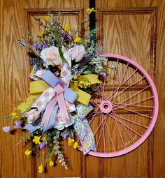 a bicycle wheel decorated with flowers and ribbons on the front door to a house or office