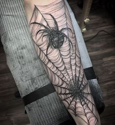 a black and white spider web tattoo on the arm