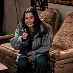 a woman sitting on top of a couch giving the thumbs up