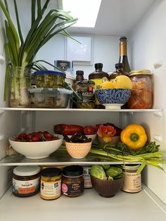 an open refrigerator filled with lots of food and condiments in bowls on the shelves