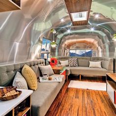 a living room filled with furniture and lots of wood flooring on top of a wooden floor