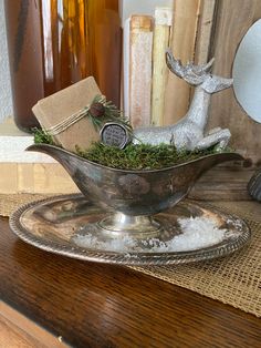 a glass bowl filled with moss sitting on top of a wooden table next to bottles