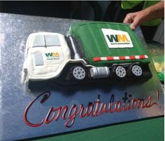 a cake shaped like a garbage truck on top of a sign