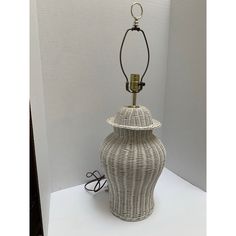 a white wicker lamp sitting on top of a table next to a light bulb