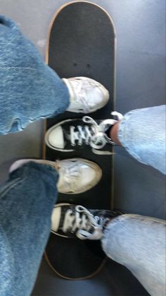 two people standing on top of a skateboard with their feet in the air and one person wearing white sneakers