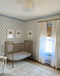 a baby's crib in the corner of a room with curtains on the windowsill