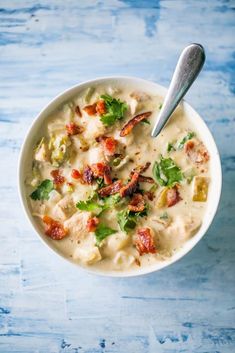 a white bowl filled with soup on top of a blue table next to a spoon