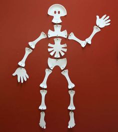 a skeleton made out of paper on a red wall