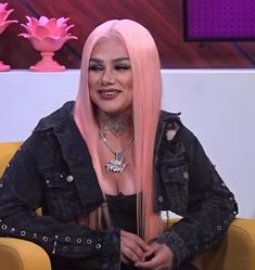 a woman with pink hair sitting in a chair