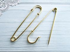 two pairs of fishing hooks sitting on top of a white table next to a lace doily